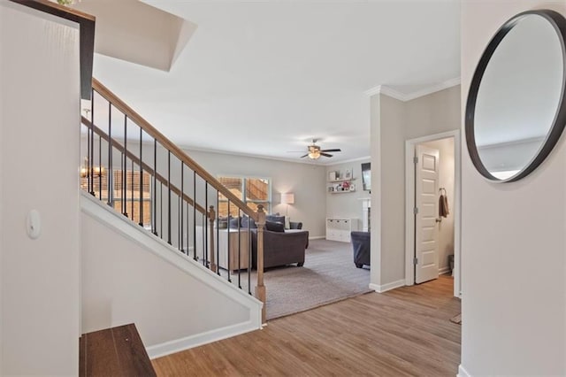 entrance foyer featuring ceiling fan, stairway, wood finished floors, baseboards, and crown molding