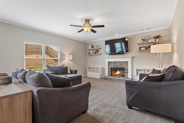 living area featuring a ceiling fan, carpet floors, ornamental molding, a stone fireplace, and baseboards