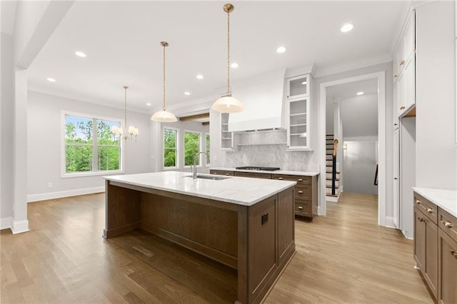 4860 Grandview Ct, Flowery Branch, GA 30542 - kitchen featuring backsplash, gas stovetop, light wood finished floors, glass insert cabinets, and a center island with sink