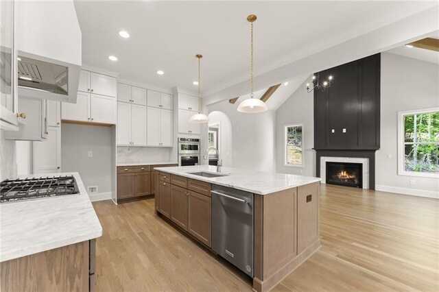 4860 Grandview Ct, Flowery Branch, GA 30542 - kitchen with lofted ceiling, appliances with stainless steel finishes, white cabinets, light wood-type flooring, and a large fireplace