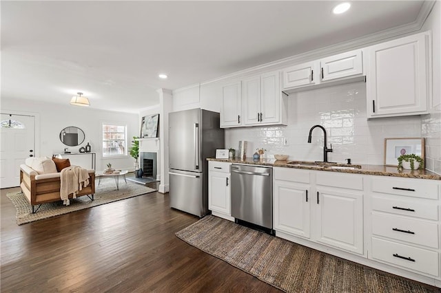 kitchen with dark wood-type flooring, a sink, stone countertops, tasteful backsplash, and appliances with stainless steel finishes