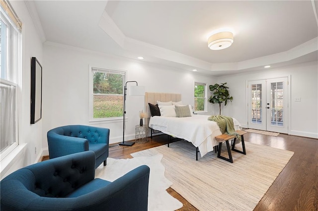 bedroom featuring a tray ceiling, access to outside, wood finished floors, and french doors