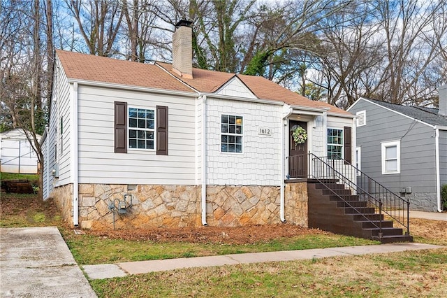 view of front of property featuring a shingled roof and a chimney