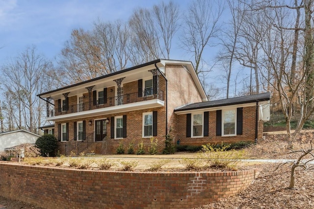 view of front of home with brick siding and a balcony