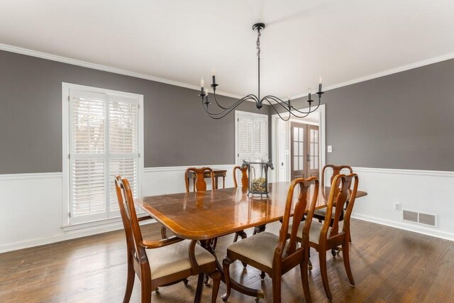 dining area with ornamental molding, a wainscoted wall, visible vents, and dark wood finished floors