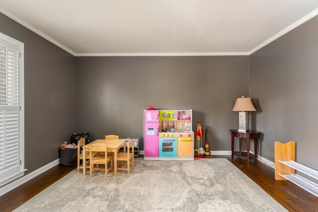 rec room with baseboards, wood finished floors, and crown molding