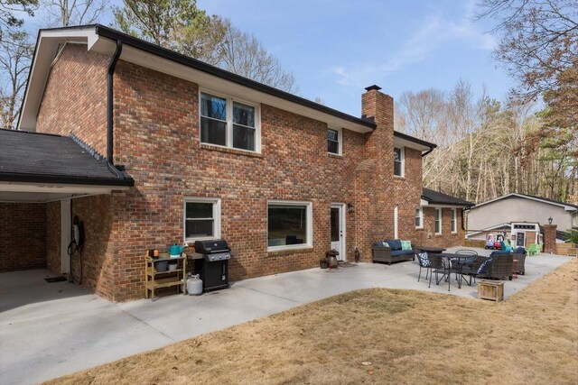 rear view of property featuring brick siding, an outdoor living space, a yard, a chimney, and a patio area