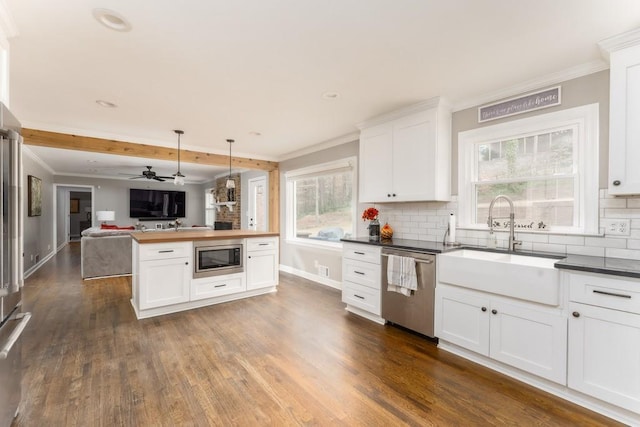 kitchen featuring open floor plan, appliances with stainless steel finishes, backsplash, and dark wood-style floors