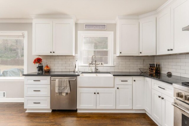 kitchen featuring dark countertops, dark wood-style floors, stainless steel appliances, crown molding, and a sink