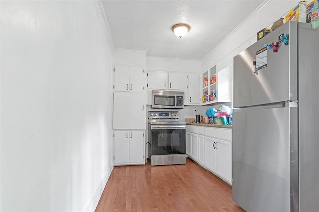 kitchen featuring white cabinets, crown molding, light hardwood / wood-style floors, and stainless steel appliances