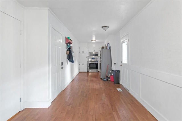 hall featuring light wood-type flooring and crown molding