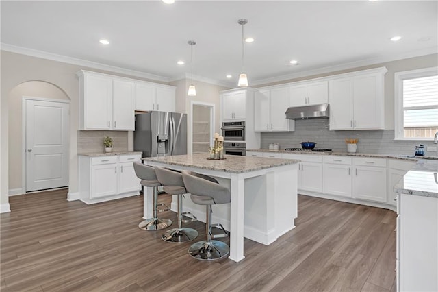 kitchen with backsplash, crown molding, appliances with stainless steel finishes, and under cabinet range hood