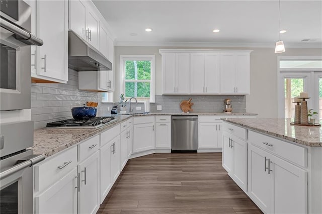 kitchen with crown molding, under cabinet range hood, appliances with stainless steel finishes, and a healthy amount of sunlight