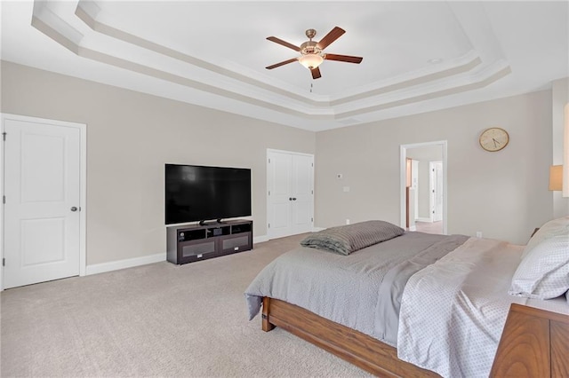 bedroom with light colored carpet, a raised ceiling, ceiling fan, and baseboards