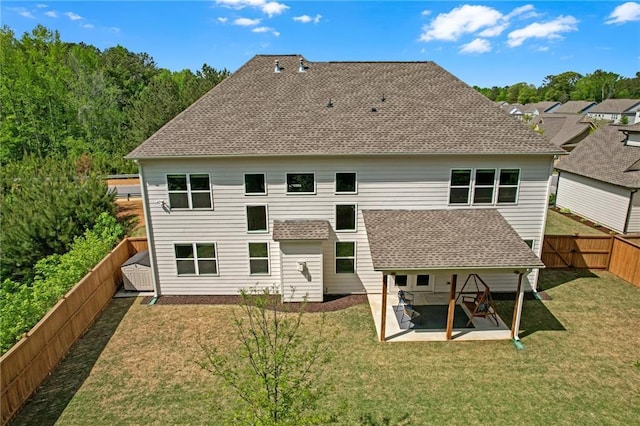 back of property with a lawn, a fenced backyard, a patio area, and a shingled roof