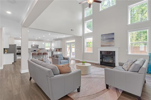 living area featuring visible vents, ceiling fan, wood finished floors, and a fireplace
