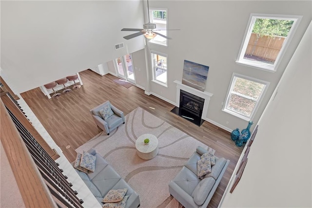 living room with visible vents, wood finished floors, baseboards, a high ceiling, and a ceiling fan
