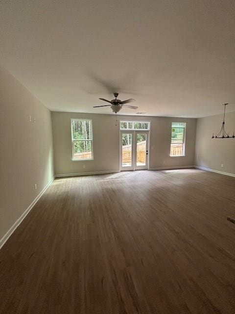 empty room featuring dark hardwood / wood-style flooring and ceiling fan with notable chandelier