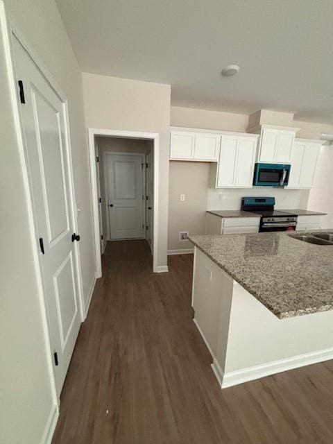 kitchen with electric range, dark hardwood / wood-style floors, light stone counters, and white cabinetry