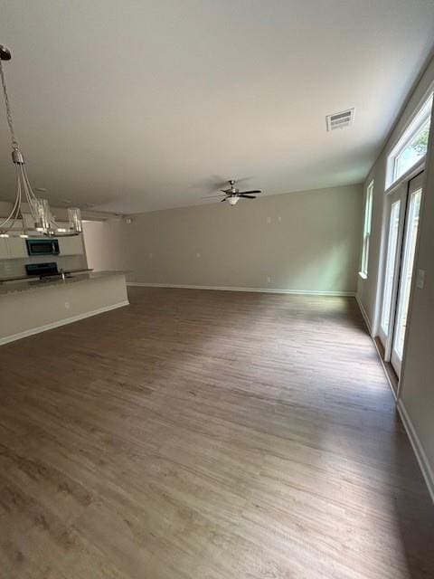 unfurnished living room featuring ceiling fan and dark wood-type flooring