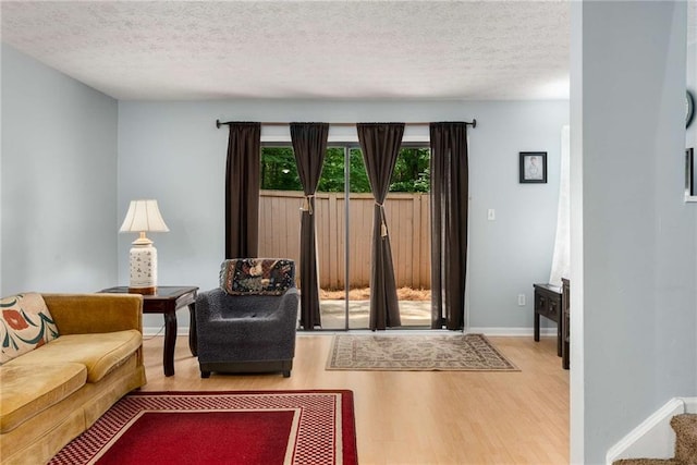 living area featuring wood finished floors, a textured ceiling, and baseboards