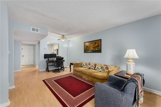 living area featuring wood finished floors, a ceiling fan, a textured ceiling, and baseboards