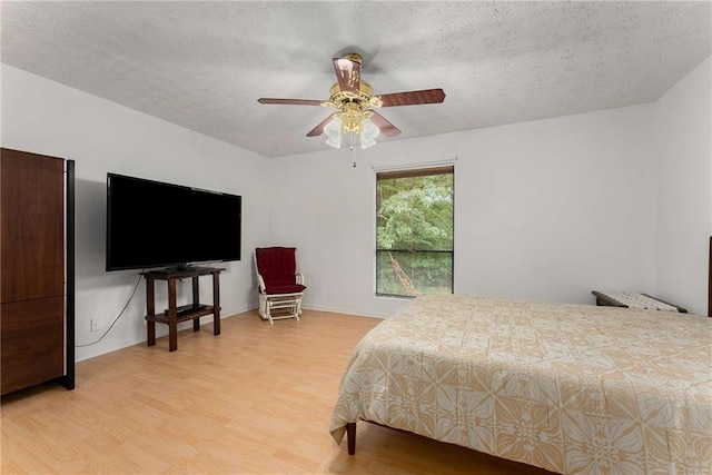 bedroom with light wood finished floors, a textured ceiling, ceiling fan, and baseboards