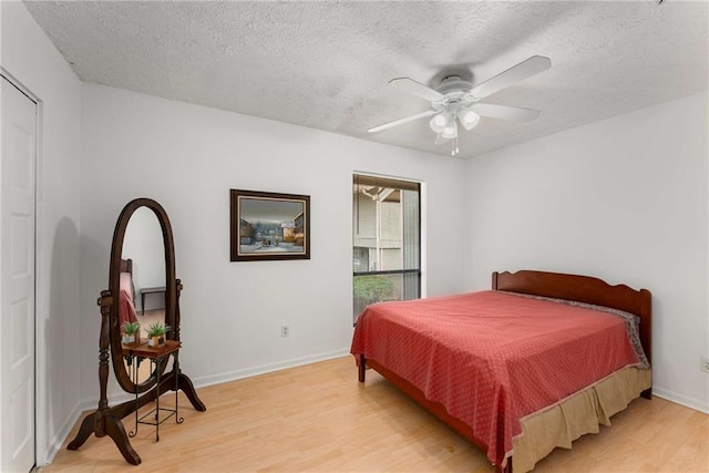 bedroom with light wood-style flooring, a textured ceiling, baseboards, and ceiling fan