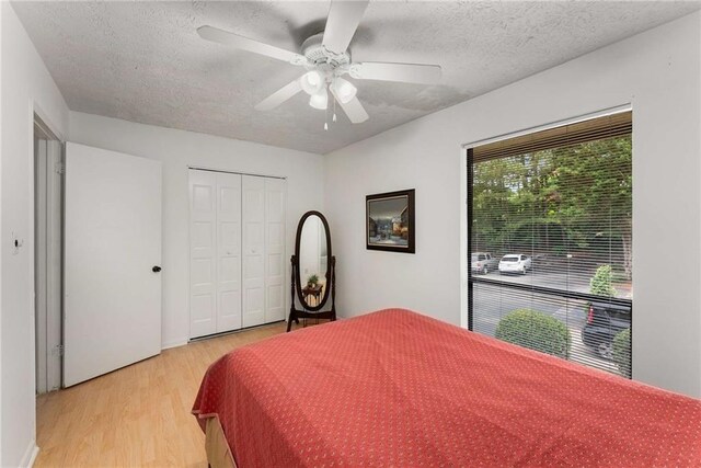 bedroom featuring light wood-style flooring, a textured ceiling, a closet, and ceiling fan