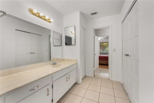 ensuite bathroom featuring vanity, tile patterned flooring, and baseboards