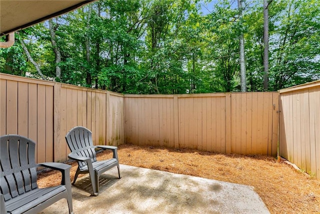 view of patio / terrace with a fenced backyard and view of wooded area