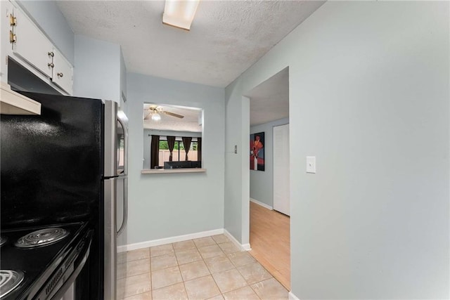 kitchen with white cabinetry, stainless steel electric stove, ceiling fan, light tile patterned floors, and a textured ceiling
