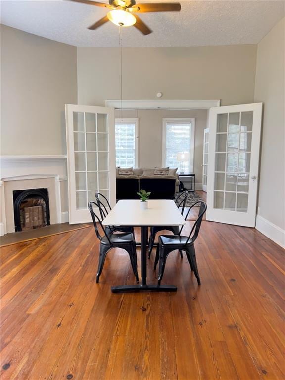 632 Monroe St, Macon, GA 31201 - dining room featuring ceiling fan, wood-type flooring, baseboards, a fireplace, and a textured ceiling