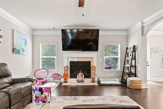 living room featuring plenty of natural light, dark hardwood / wood-style floors, crown molding, and ceiling fan