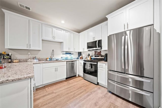 kitchen with light wood-type flooring, stainless steel appliances, white cabinetry, and sink