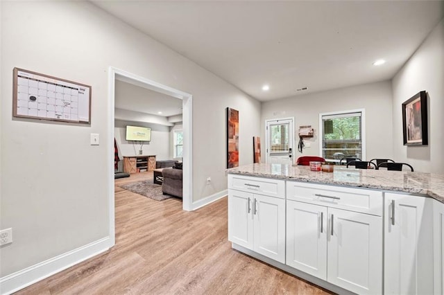 kitchen with light stone countertops, white cabinets, and light hardwood / wood-style floors