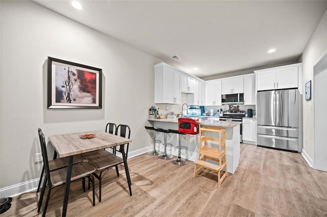 kitchen with white cabinets, kitchen peninsula, and stainless steel appliances