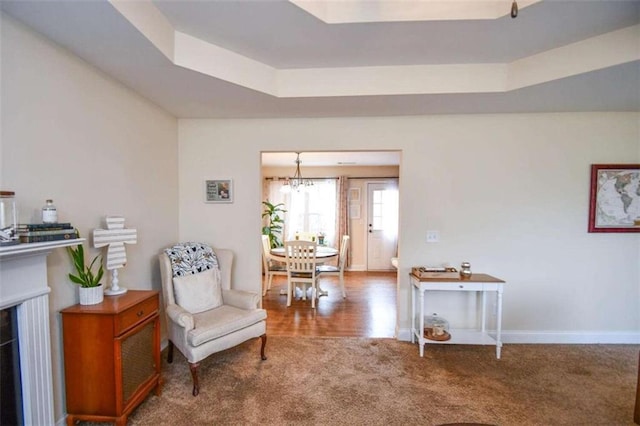 sitting room with an inviting chandelier, carpet flooring, and a raised ceiling