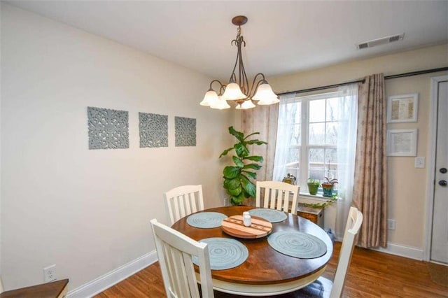 dining room with hardwood / wood-style flooring and a chandelier