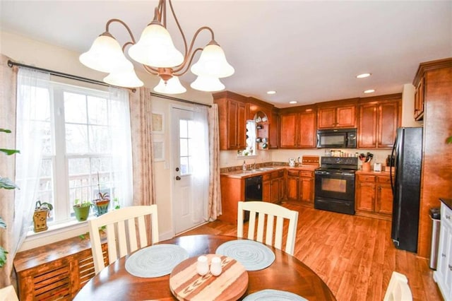 kitchen featuring decorative light fixtures, sink, a chandelier, black appliances, and light wood-type flooring