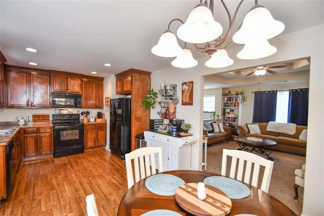 kitchen featuring ceiling fan, pendant lighting, light hardwood / wood-style floors, and black appliances