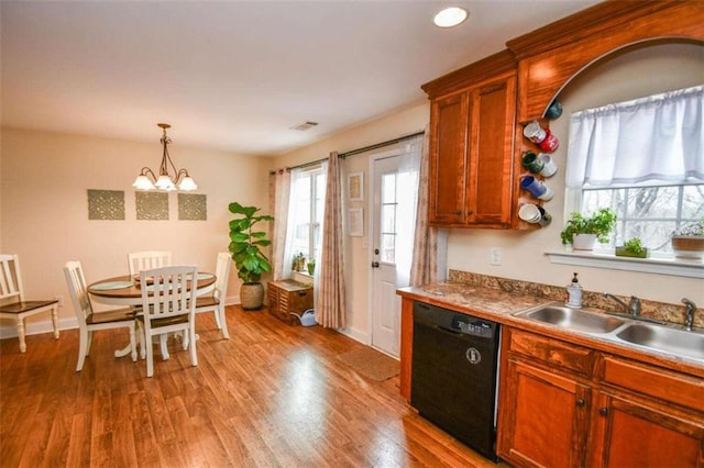 kitchen with sink, black dishwasher, decorative light fixtures, a chandelier, and light wood-type flooring