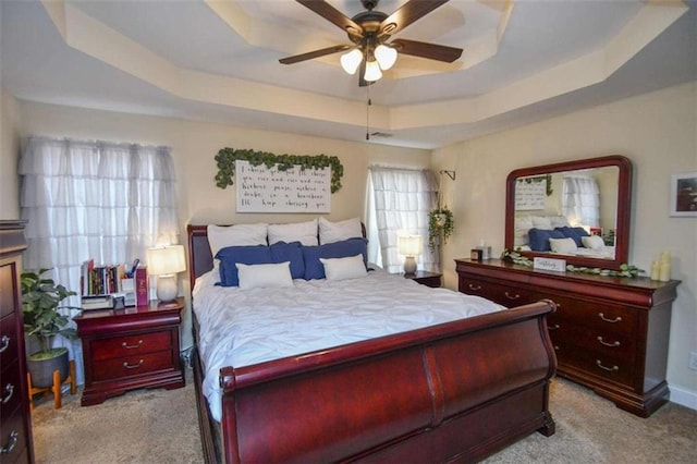 carpeted bedroom with a tray ceiling and ceiling fan