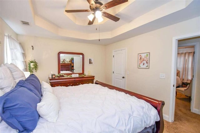 bedroom featuring carpet floors, ceiling fan, and a tray ceiling