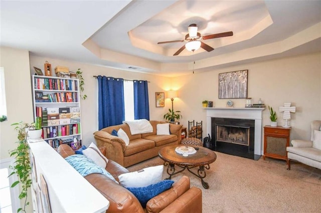 living room featuring ceiling fan, carpet flooring, and a raised ceiling