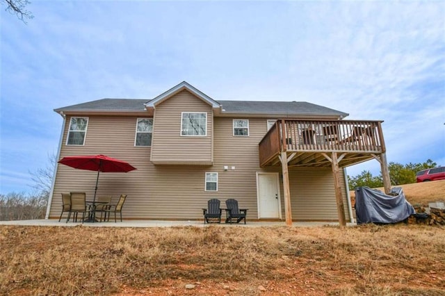 rear view of property with a wooden deck and a patio