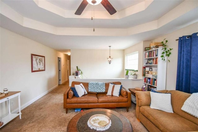 carpeted living room featuring a raised ceiling and ceiling fan