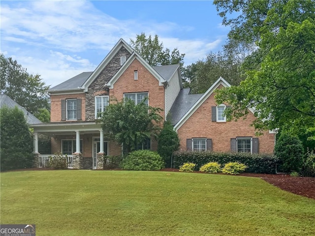 view of front of house with brick siding, stone siding, covered porch, and a front yard