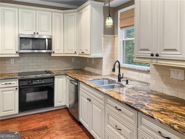 kitchen with dark wood finished floors, dark stone countertops, white cabinets, black appliances, and a sink