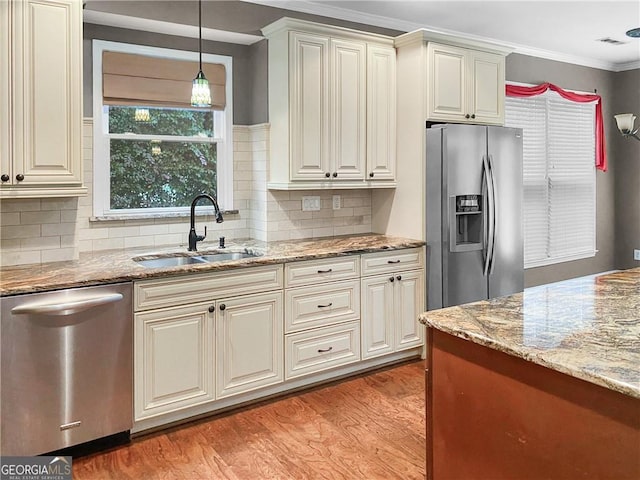 kitchen with light stone counters, light wood-type flooring, appliances with stainless steel finishes, and a sink